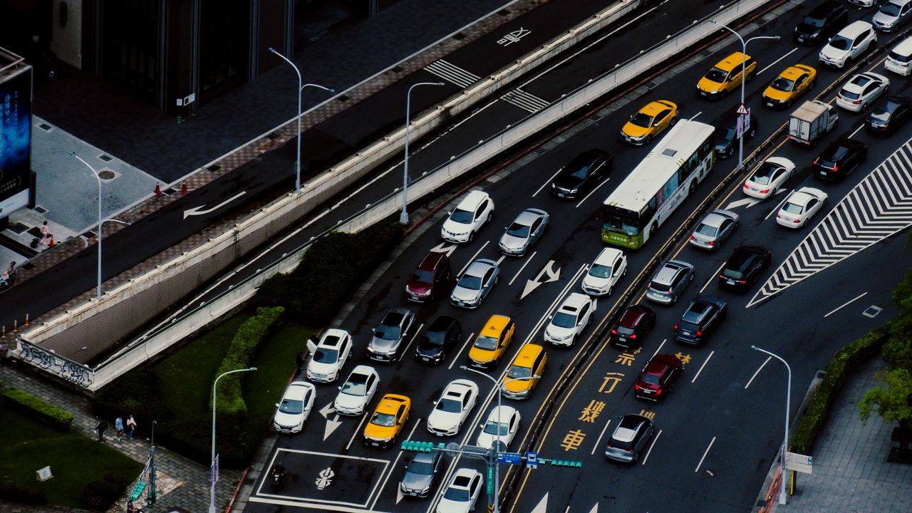 Bird's eye view of urban traffic with multiple cars, buses, and taxis on a city street.